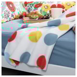 Brightly colored polka dot blanket on a floral pillow bed, with breakfast tray.