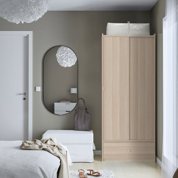 Minimalist bedroom with oak BRUKSVARA wardrobe, sliding doors, calm gray walls.