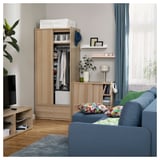 Oak wardrobe with clothes, blue sofa, side table with lamp, tv.