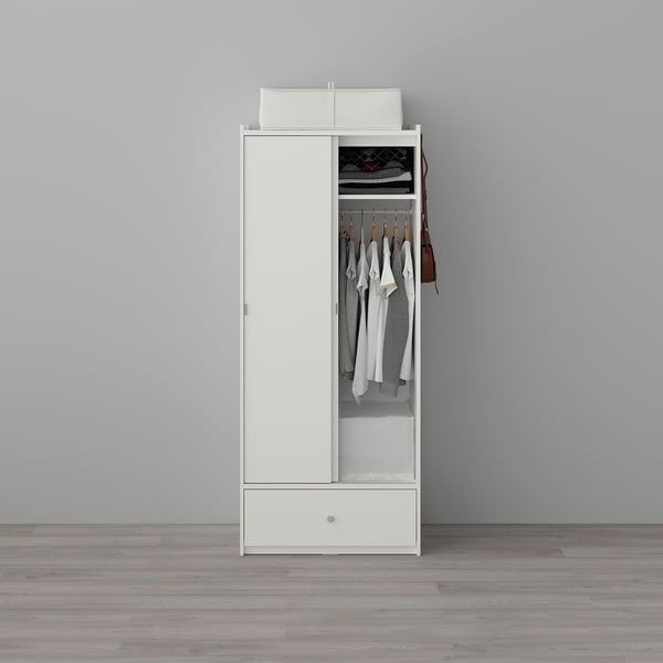 White wardrobe with sliding doors, clothes rail, shelf, and drawer. Holds garments and small items, with hooks on side.
