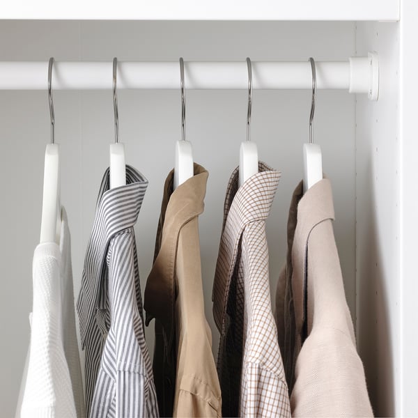 Clothes hangers on rod, displaying varied garments. Hanger grooves prevent clothing from sliding.