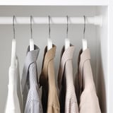 Clothes hangers on rod, displaying varied garments. Hanger grooves prevent clothing from sliding.
