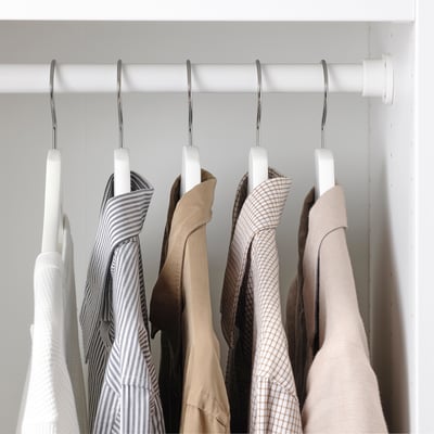 Clothes hangers on rod, displaying varied garments. Hanger grooves prevent clothing from sliding.