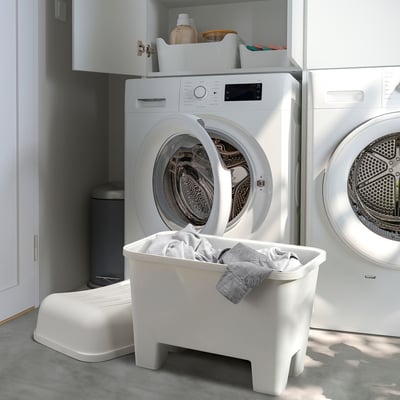 White plastic stools & washing machines in laundry room. Central stool stores laundry.