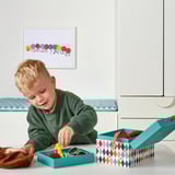Boy playing with toys on colorful, organized storage box.