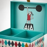 Cartoon girl lifting weights on colorful, turquoise box with compartments.