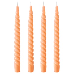 Four twisted orange candles side by side. Made of paraffin and plant-based wax, each with a cotton wick.