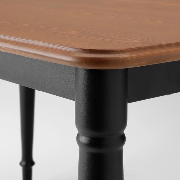 Close-up of wooden table with black metal legs, smooth, polished surface.