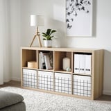 Modern storage unit with fabric boxes. Light wood & white. Holds books, vases, & plants. Fits kallax shelves. Decorative & organized.