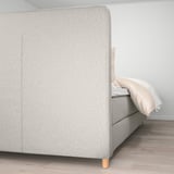 Light-colored headboard and bed frame with wooden legs, part of ikeas DUNVIK collection.