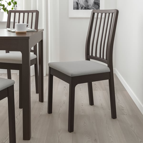 EKEDALEN extendable dining table with dark brown table, matching chairs, one with gray cushion, white mug, minimalist decor.