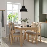 Wooden dining set in bright kitchen, large window, green cabinets, self-storing table. Cozy & modern.
