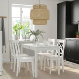 Bright kitchen with white EKEDALEN dining set, light wood floor, black cabinets, plant, vase, and hanging lamps.