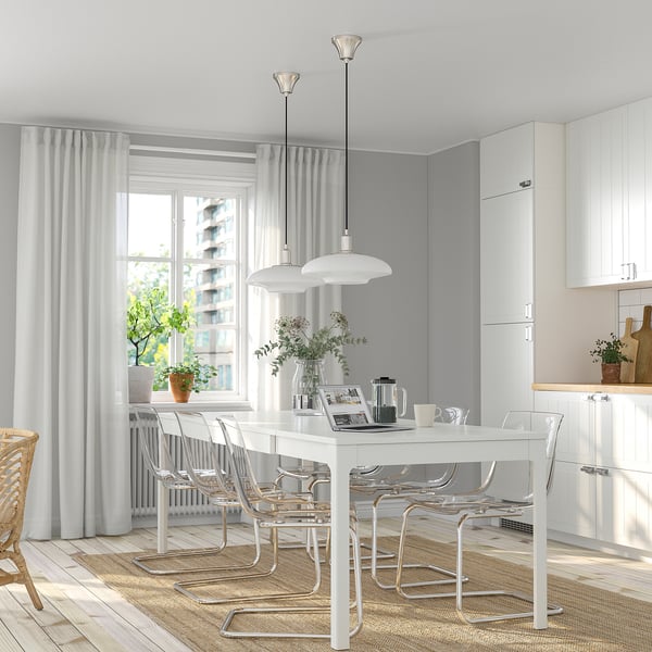 White dining table with clear chairs, two pendant lights, beside a window. Fits six.