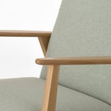 Close-up of stylish retro armchair with solid wood arms and cushy seat.