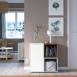 Modern living room with EKET storage. White cabinet has open/closed storage, adjustable shelves, under window, with pictures above and seating area.