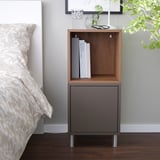 EKET bedside cabinet in modern bedroom. Or, to include more details: modern bedroom with grey EKET cabinet and wooden shelf.