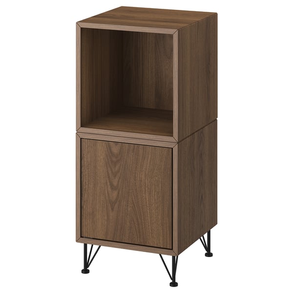 An EKET cabinet in walnut color with open and closed compartments. It stands on black metal legs, blending modern and mid-century styles.