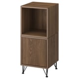 An EKET cabinet in walnut color with open and closed compartments. It stands on black metal legs, blending modern and mid-century styles.
