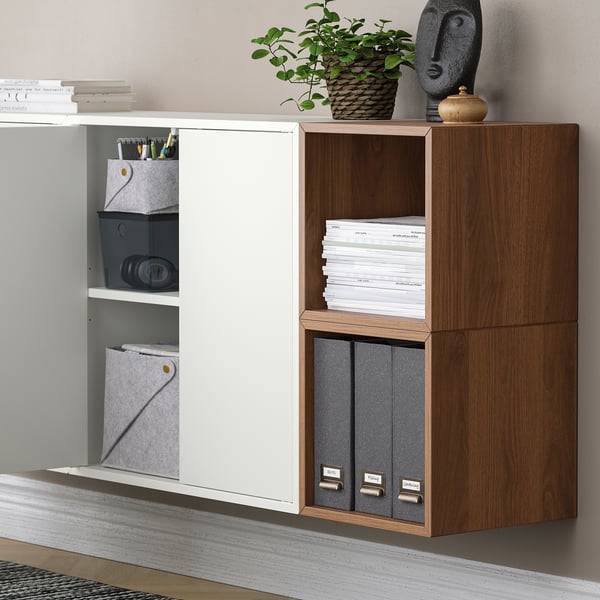 Wall-mounted EKET storage units with shelves and cabinets, displaying books, supplies, and decorative items.