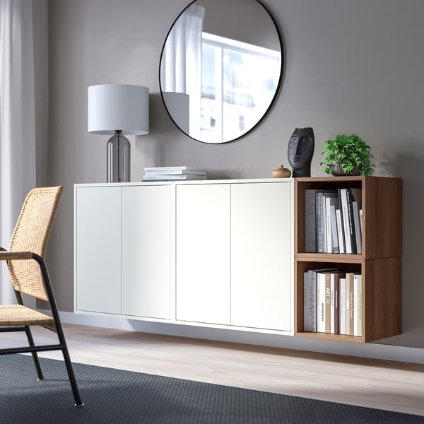 Modern room with EKET cabinets, books, lamp, sculpture, wicker chair, and large mirror.