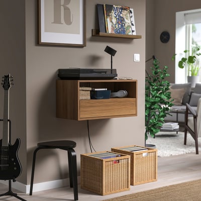 Modern record player with wicker storage, wall poster, clock, and plant.