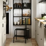 Modern kitchen with open shelves, organized food, and a step stool.
