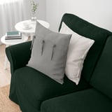 Dark green sofa with grey and white pillows, cozy and inviting.