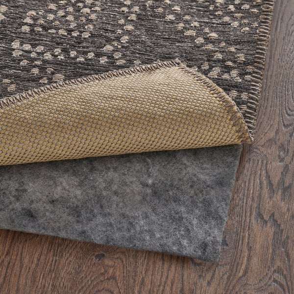 A corner of a flat-woven rug with visible felt backing, designed for easy chair movement and cleaning.
