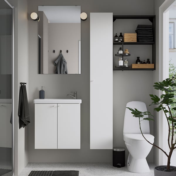 Modern bathroom a white ENHET cabinet with a mirror above, black accents, and a houseplant by the toilet.