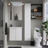 Modern bathroom a white ENHET cabinet with a mirror above, black accents, and a houseplant by the toilet.