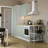 Modern kitchen with light green ENHET cabinets, white oven, open shelves with cookware, countertop appliances, potted plant, and area rug.