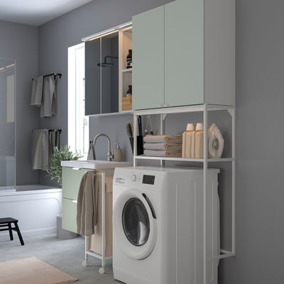 Modern laundry-bathroom combo. Light green cabinets, white appliances. Compact yet spacious.