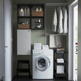 Modern laundry corner with white ENHET cabinet, shelves, and washing machine. Holds towels, detergents, and clothes neatly.