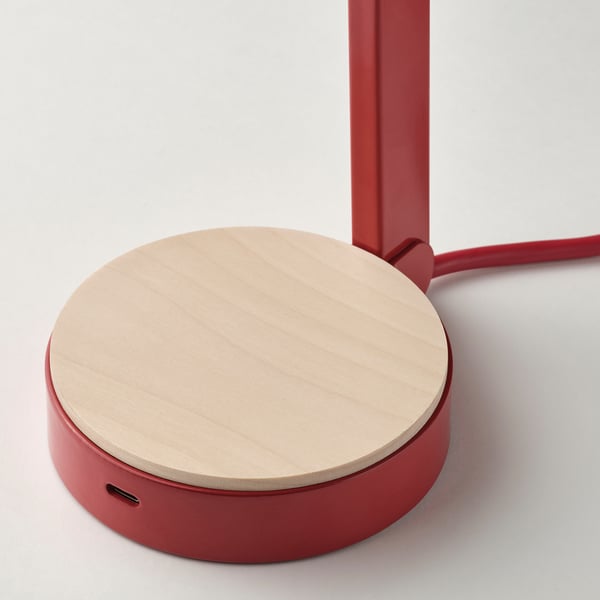Modern red desk lamp with wooden base, usb-c port, sleek design, high quality materials.