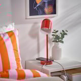 Bright red desk lamp with usb-c charging, brightening workspace beside colorful pillows.