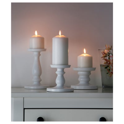 Three candles in varying heights on dresser, warm atmosphere.
