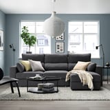 Modern living room with gray sectional sofa, adjustable headrests, and a pendant lamp above. Large window brings in natural light.