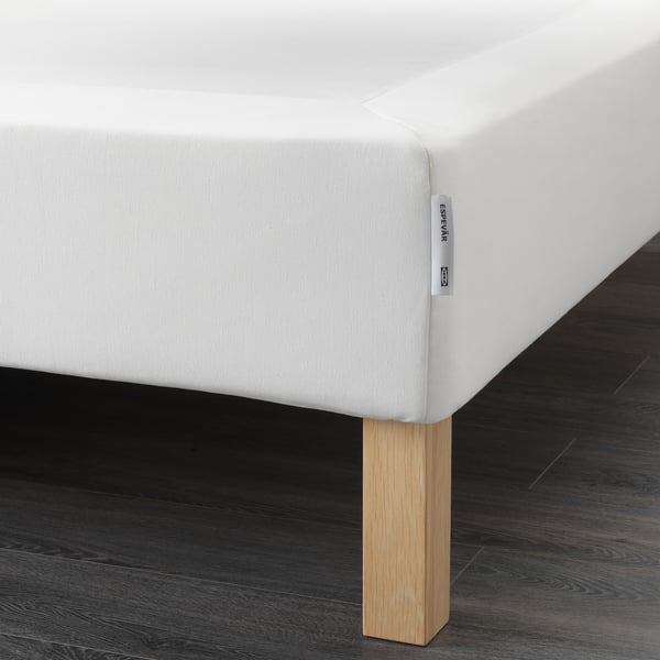 A white bed on wooden legs, offering support and height.