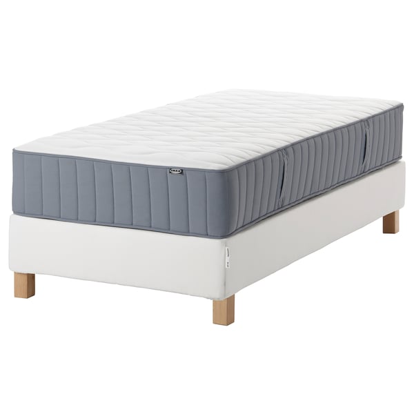 White IKEA twin mattress on a white bed frame with wooden legs, featuring gray sides and a padded top.