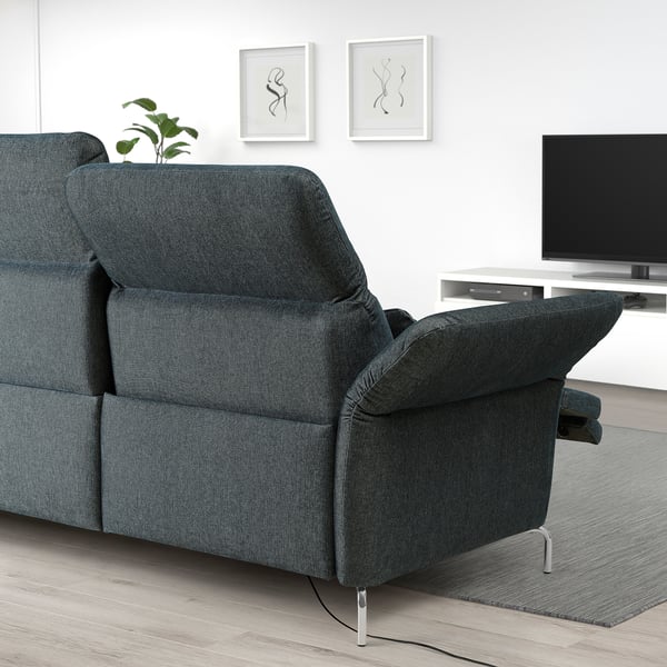 Modern dark grey FAMMARP sofa with adjustable headrests and armrests. Positioned against a white wall with art and tv, with a plant on the armrest.