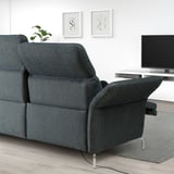 Modern dark grey FAMMARP sofa with adjustable headrests and armrests. Positioned against a white wall with art and tv, with a plant on the armrest.