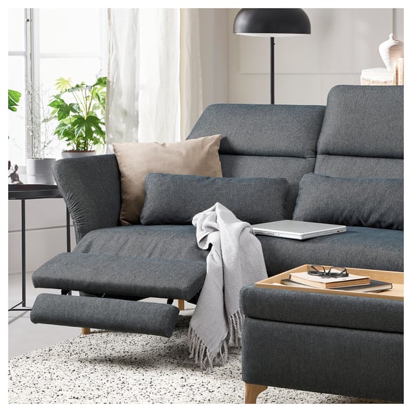 Modern dark grey FAMMARP sectional sofa with adjustable headrests and a gray throw blanket draped over it, situated in a cozy living room setting.