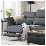 Modern dark grey FAMMARP sectional sofa with adjustable headrests and a gray throw blanket draped over it, situated in a cozy living room setting.