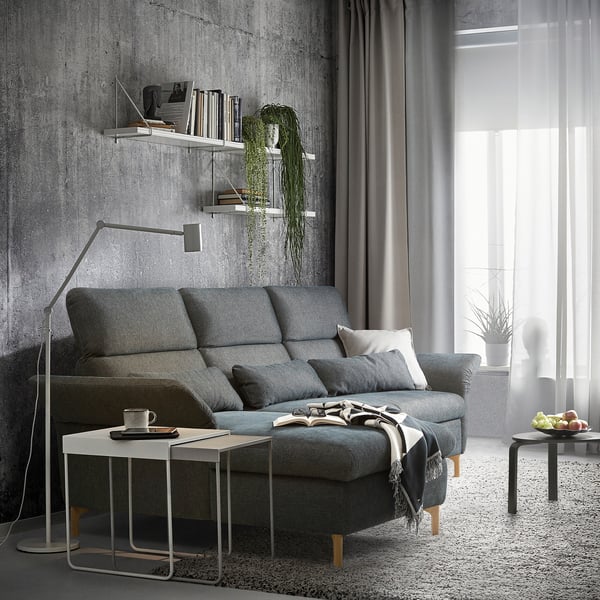 Modern gray sofa in living room with concrete walls and floor lamp.