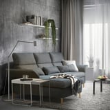 Modern gray sofa in living room with concrete walls and floor lamp.