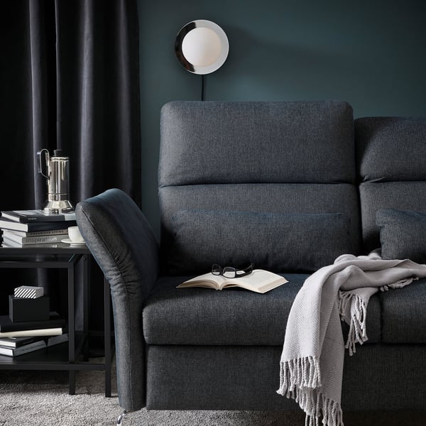 Dark grey FAMMARP sofa with adjust. Headrests, blanket, side table with books and coffee.