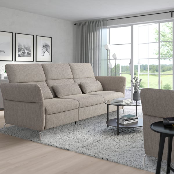 Modern living room with gray FAMMARP sofa, armchair, glass table, art, and large windows.