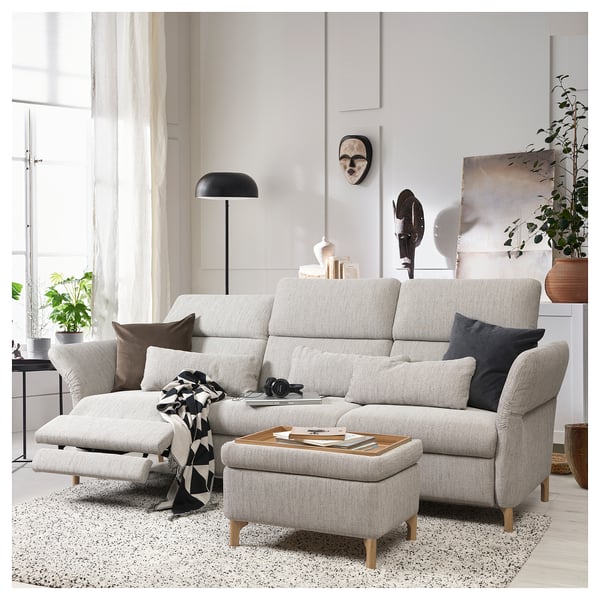Modern living room with light gray FAMMARP sofa, black pillows, wooden legs, and adjustable headrests. Decorated with plants and artwork.