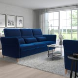 Modern living room with large navy blue FAMMARP sofa, matching blue armchair, and neutral decor. Large windows provide ample natural light.